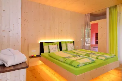 a bedroom with a large bed with green sheets at Rumlhof in Bressanone