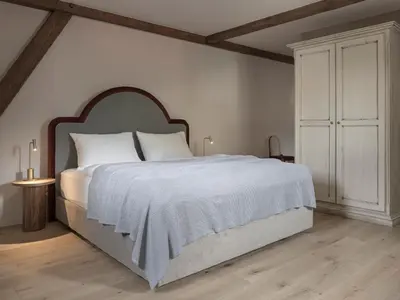 a white bedroom with a large bed with a wooden headboard at Villa Helvetia in Merano