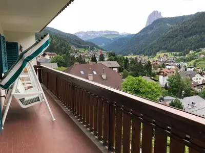 a balcony with a lawn chair and a view of a town at Appartements Arnica in Ortisei