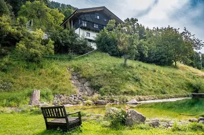 a bench sitting on a hill next to a house at Burgerhof in San Genesio Atesino