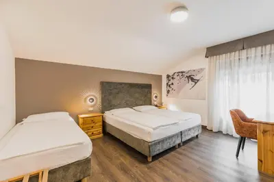 a bedroom with two beds and a desk and a desk at Suàn Hotel in Ziano di Fiemme
