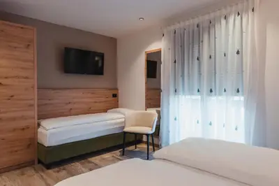 a hotel room with two beds and a tv at Suàn Hotel in Ziano di Fiemme