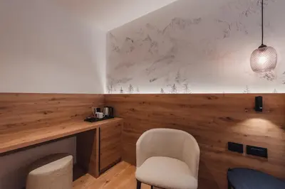 a room with a desk and two chairs and a table at Suàn Hotel in Ziano di Fiemme
