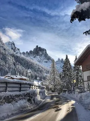 a road covered in snow next to a mountain at Chalet Prà delle Nasse in San Martino di Castrozza