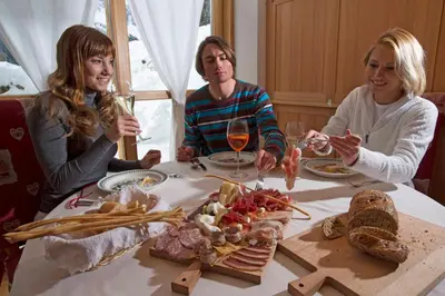 a group of people sitting around a table with food at Chalet Prà delle Nasse in San Martino di Castrozza