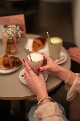 a woman holding a cup of coffee at a table with food at Kuntino Suites in Merano
