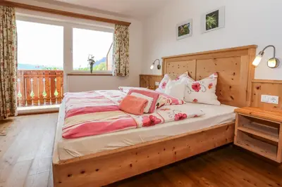 a bedroom with a large bed with a wooden headboard at Bio Kräuterhof Oberpalwitter in Barbiano
