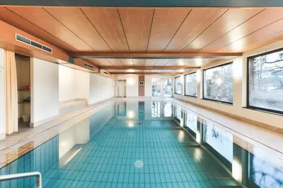 a swimming pool with a wooden ceiling and blue tile floors at Hotel Gasthof Stern in Nova Ponente
