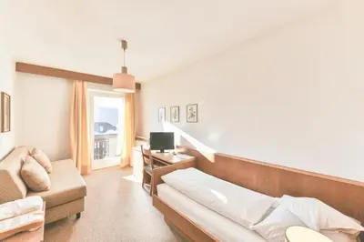 a living room with a couch and a television at Hotel Gasthof Stern in Nova Ponente