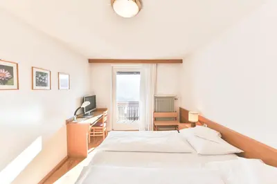 a bedroom with a bed and a desk and a window at Hotel Gasthof Stern in Nova Ponente
