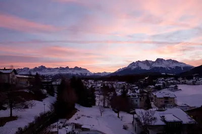 a view of a town in the snow at sunset at Hotel Gasthof Stern in Nova Ponente