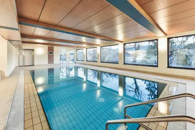 a swimming pool in a house with windows at Hotel Gasthof Stern in Nova Ponente