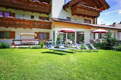 a group of chairs and umbrellas in the yard of a house at Garni Cristin & Dep Antina in Colfosco