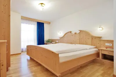 a bedroom with a large bed with a wooden headboard at Garni Cristin & Dep Antina in Colfosco