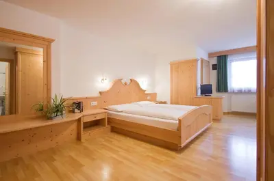 a bedroom with a large bed and a desk at Garni Cristin & Dep Antina in Colfosco