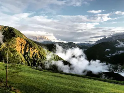 a view of a mountain valley with clouds in a field at Alpinus Agriturism in San Martino in Badia