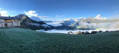 a house on top of a hill with a mountain at Alpinus Agriturism in San Martino in Badia