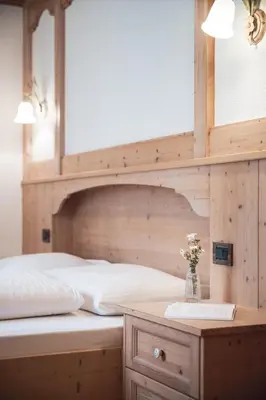 a bedroom with a large bed with a wooden headboard at Ciasa Altonn in Colfosco
