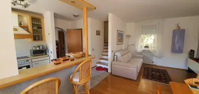 a kitchen and living room with a table and chairs at Casa Mia in Vadena