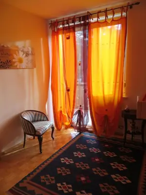 a room with orange and yellow curtains and a chair at Casa Mia in Vadena