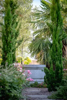 a garden with trees and flowers and a wall at Garni Hotel Peterlinhof in Caldaro