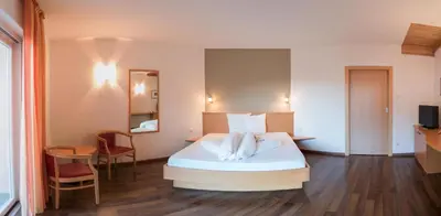 a bedroom with a bed and a table and a chair at Garni Hotel Peterlinhof in Caldaro