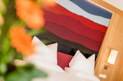 a bed with white pillows in front of a flag at Hotel Hasslhof in Caldaro