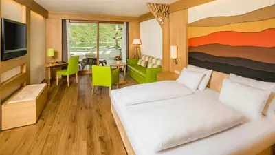 a hotel room with a bed and a living room at Hotel Hasslhof in Caldaro