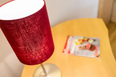 a red lamp sitting on a table next to a book at Hotel Hasslhof in Caldaro