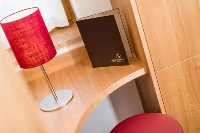 a red lamp sitting on a desk next to a book at Hotel Hasslhof in Caldaro