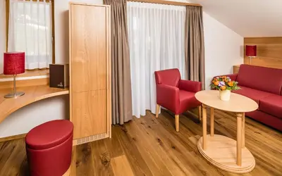 a living room with a red couch and a table at Hotel Hasslhof in Caldaro