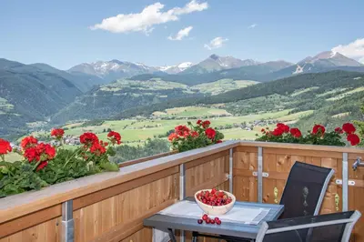 a table and chair on a balcony with flowers at Forchnerhof Panorama- Rienzschlucht in Rodengo