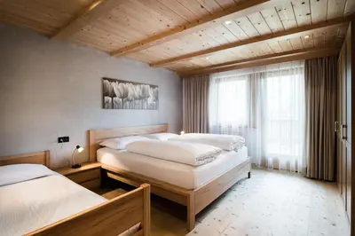 two beds in a room with wooden ceilings at Apartments Tino in La Valle