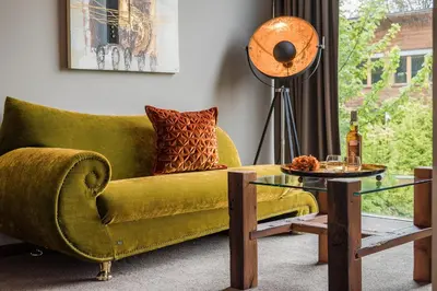 a living room with a green couch and a glass table at Hotel Restaurant Kirchsteiger in Vollan