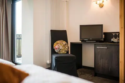 a hotel room with a chair and a television at Hotel Restaurant Kirchsteiger in Vollan