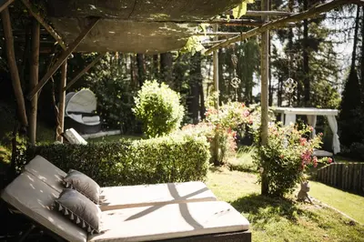 a white couch sitting under a pergola in a garden at Boutique Pension Erlacher - Adults Only in Villandro