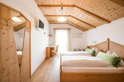 a bedroom with two beds in a room with wooden ceilings at Boutique Pension Erlacher - Adults Only in Villandro