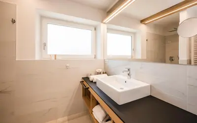 a white bathroom with a sink and a mirror at Boutique Pension Erlacher - Adults Only in Villandro
