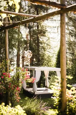 a canopy bed in a garden with flowers at Boutique Pension Erlacher - Adults Only in Villandro