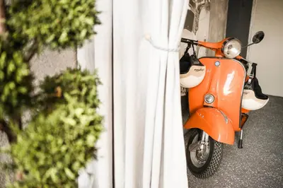 an orange scooter parked next to a white curtain at Boutique Pension Erlacher - Adults Only in Villandro