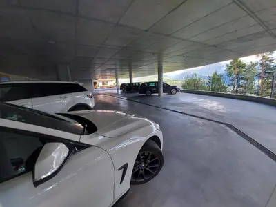 a white car parked in a garage with two cars at Boutique Pension Erlacher - Adults Only in Villandro