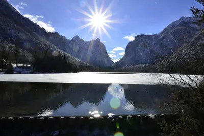 a reflection of the sun in a lake with mountains at Haus Cosso in Villabassa