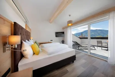 a bedroom with a bed with a view of a balcony at Appartement-Hotel Anthea in Tirolo