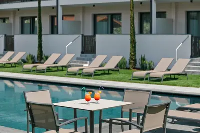 two drinks on a table next to a swimming pool at Appartement-Hotel Anthea in Tirolo