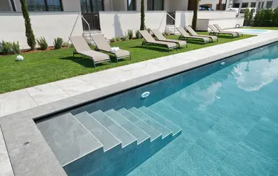a swimming pool with lounge chairs next to a building at Appartement-Hotel Anthea in Tirolo