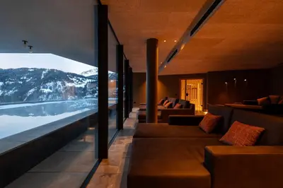 a living room with couches and a view of a mountain at Hotel Alpenrose Dolomites in La Valle