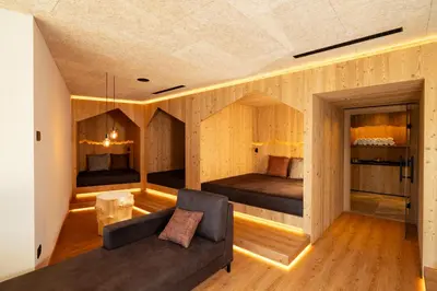 a living room with a couch and two beds at Hotel Alpenrose Dolomites in La Valle