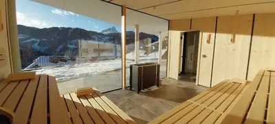 a room with benches and a view of a mountain at Hotel Alpenrose Dolomites in La Valle