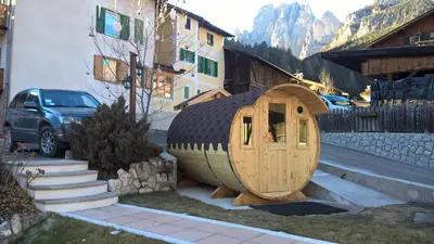 a small wooden hobbit house sitting next to a building at Residence Le Rose in Pozza di Fassa