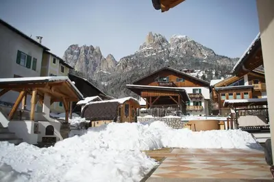 a group of snow piles up in a town with mountains at Residence Le Rose in Pozza di Fassa